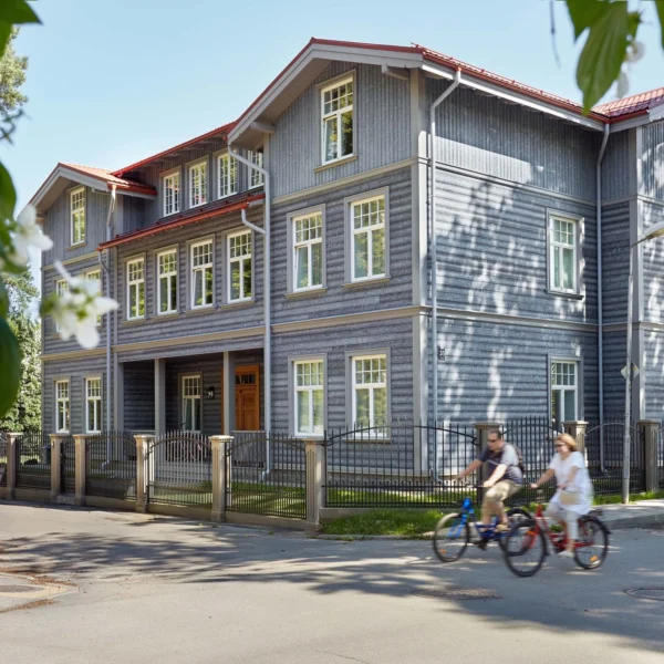 Two people riding bikes in front of a building.