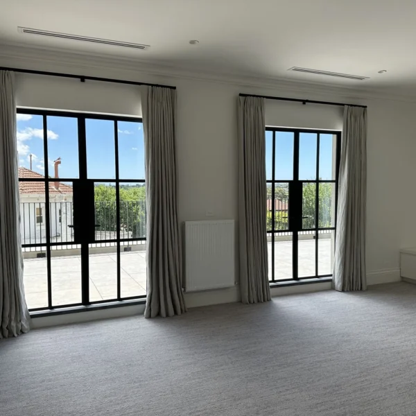 A room with two large windows and a tile floor.