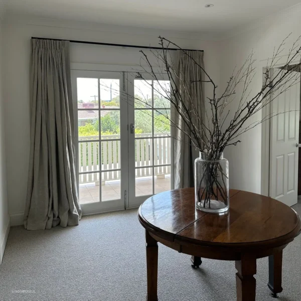 A table with branches in it and a vase on the floor