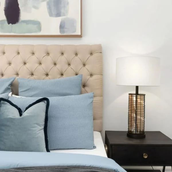 A bed with blue pillows and a lamp on the side.