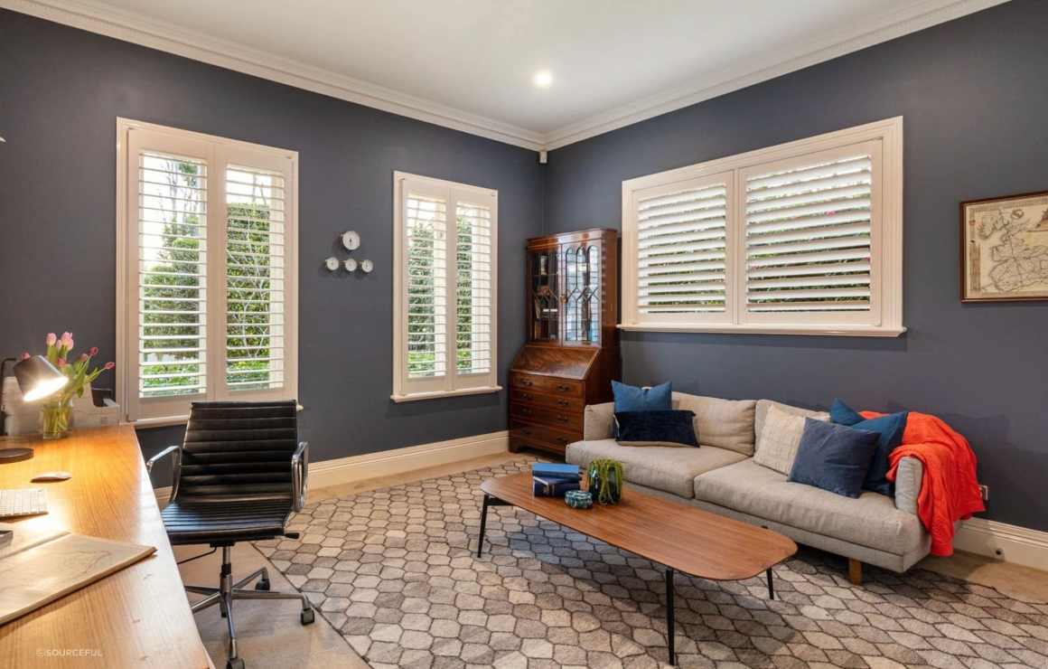 A living room with blue walls and white shutters.