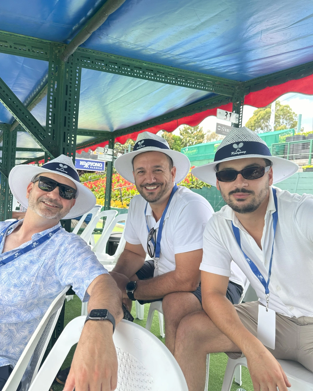 Three men sitting on a bench wearing hats.