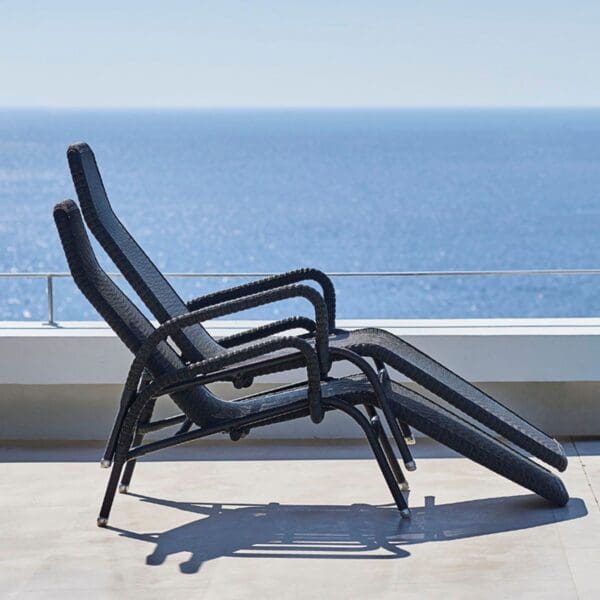 A lounge chair on the patio overlooking the ocean.