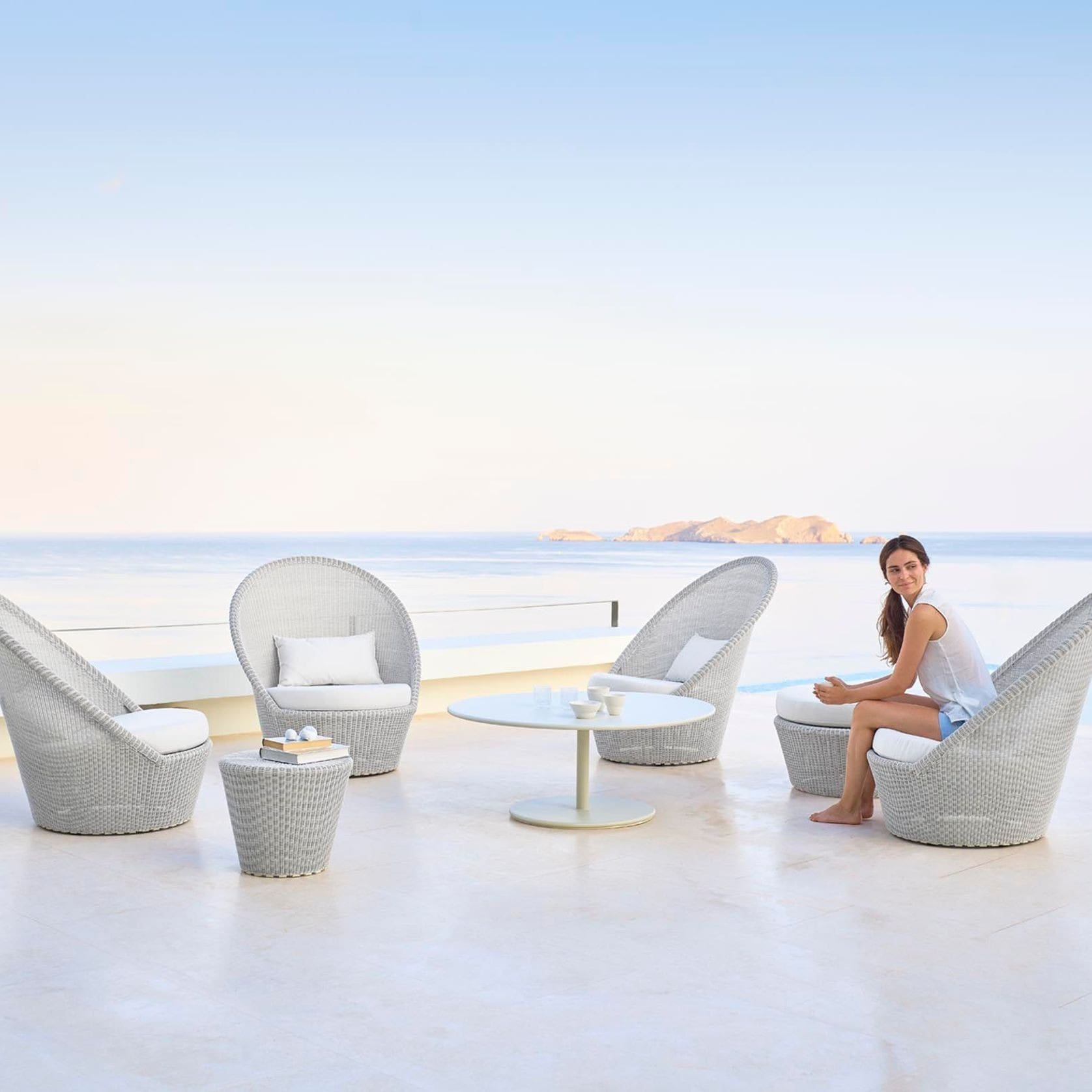 A woman sitting on the ground next to some chairs.