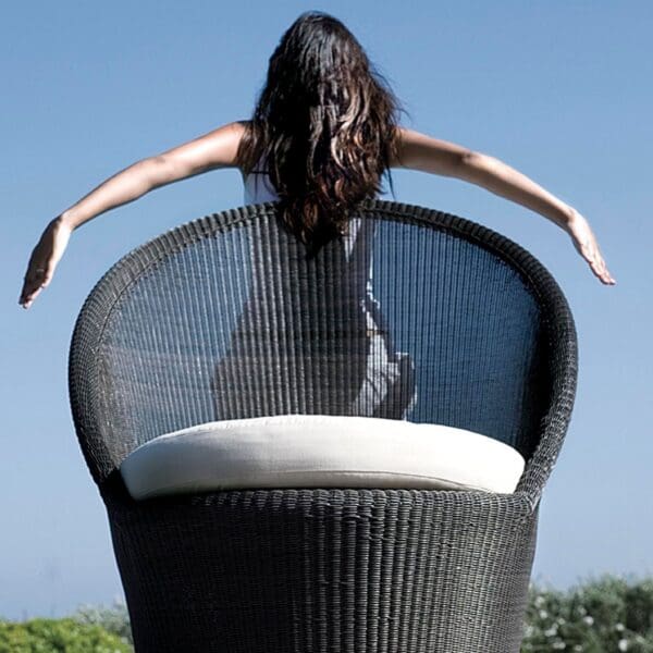 A woman sitting on top of a chair with arms outstretched.