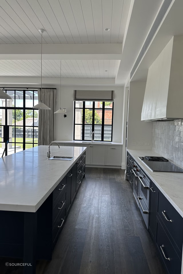 A large kitchen with white counters and black cabinets.