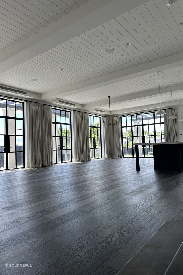 A large room with many windows and wooden floors.