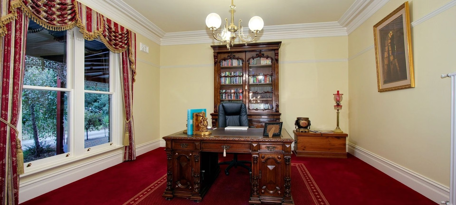 A large wooden desk in front of a bookcase.