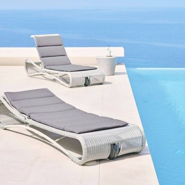 Two lounge chairs are next to a pool.