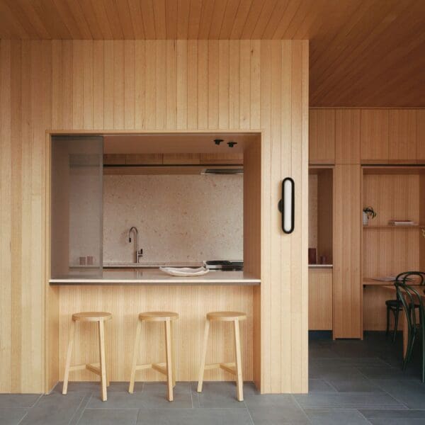 A kitchen with wooden walls and three stools.