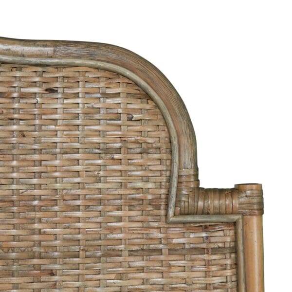 A close up of the corner of a bed with wicker headboard.