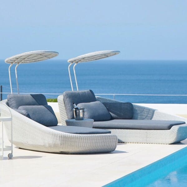 A pool with two lounge chairs and an umbrella.