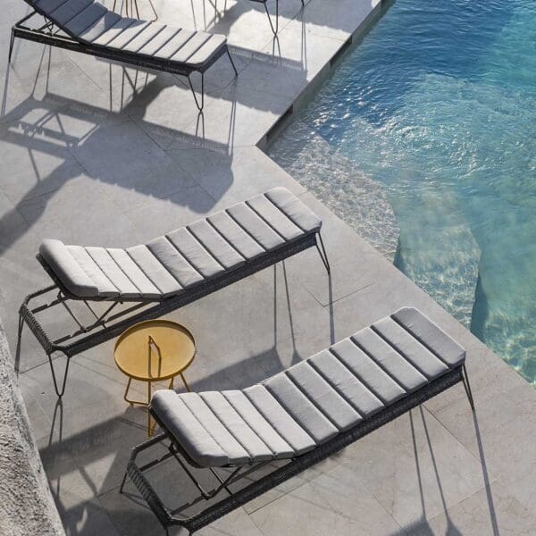 A pool with three lounge chairs and a table