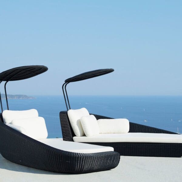 Two black and white lounge chairs with a sky background