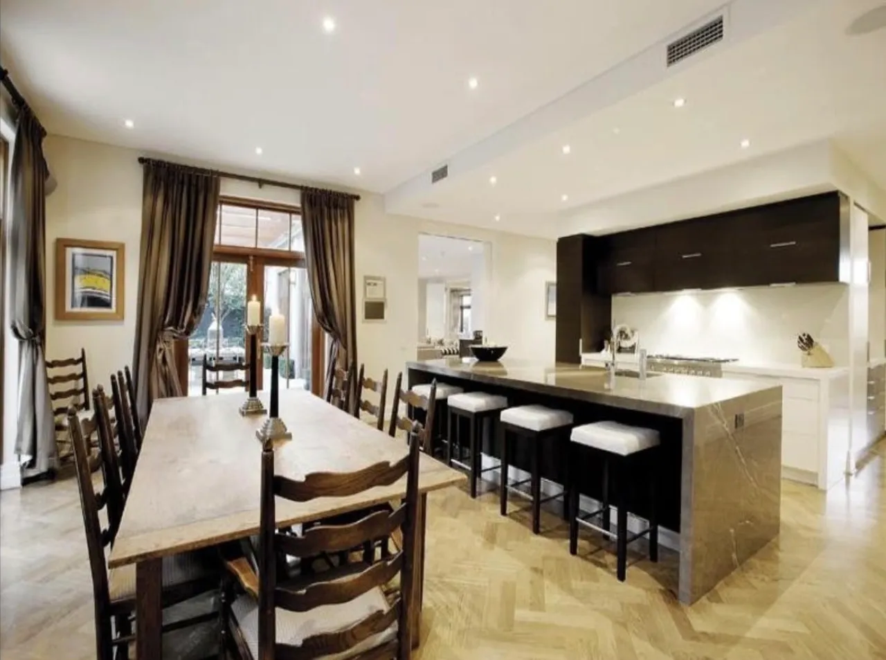 A large dining room table in front of a kitchen.